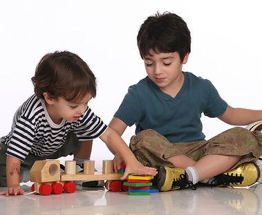Two children playing with wooden toys on the floor